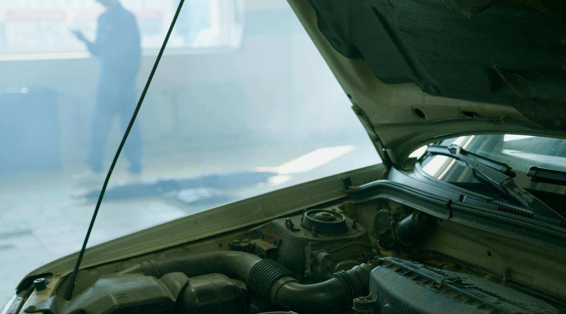 Open car hood and engine bay in an auto repair setting